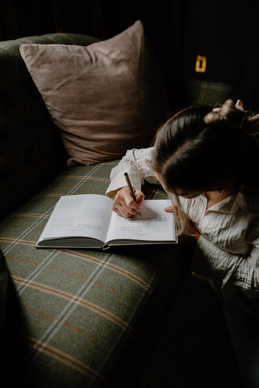 A parent on the sofa, writing in the book