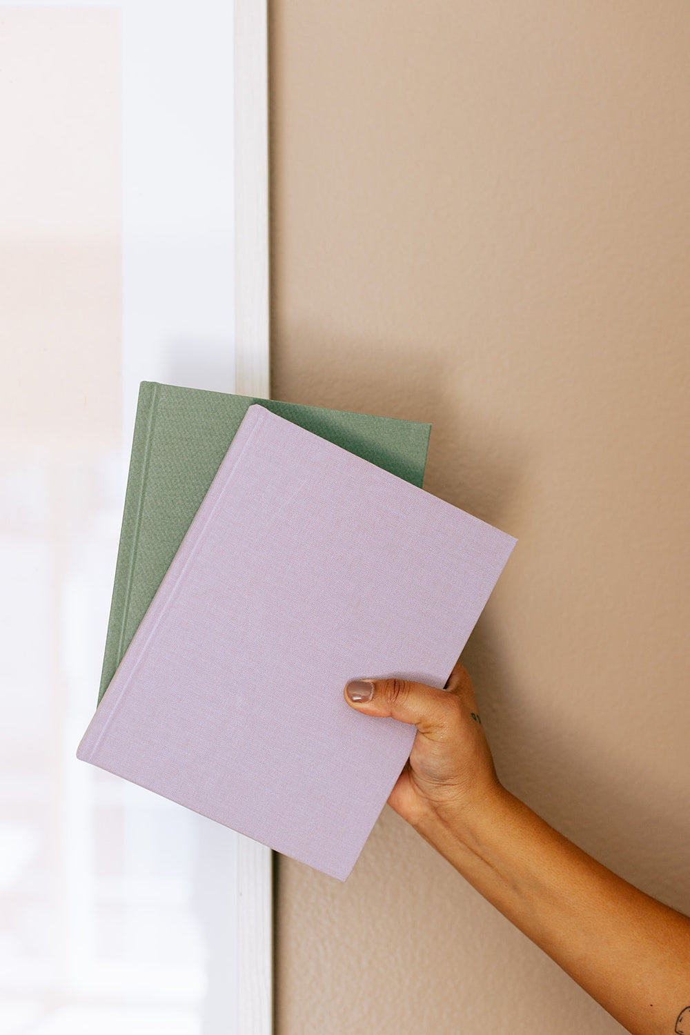 A hand pulling a Lavender and a Forest book off the shelf